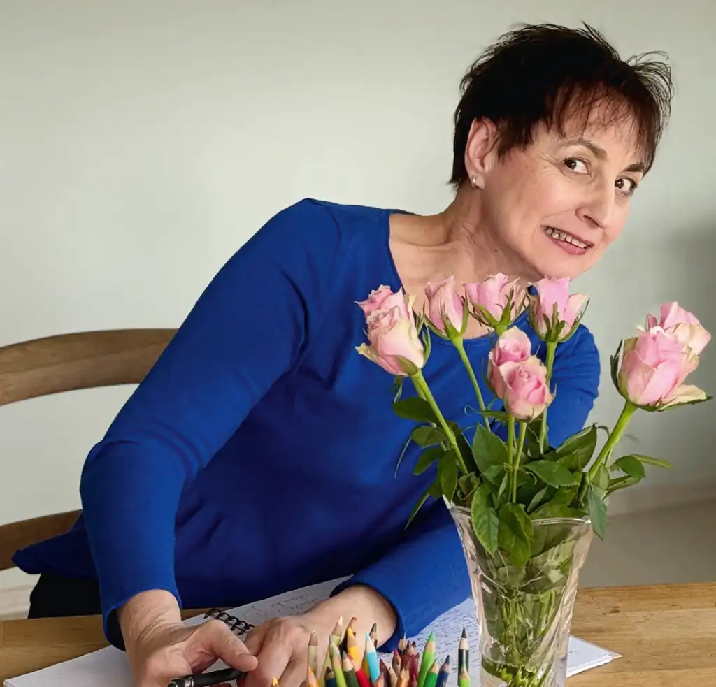 Christine Schlör guckt hinter den Blumen hervor.