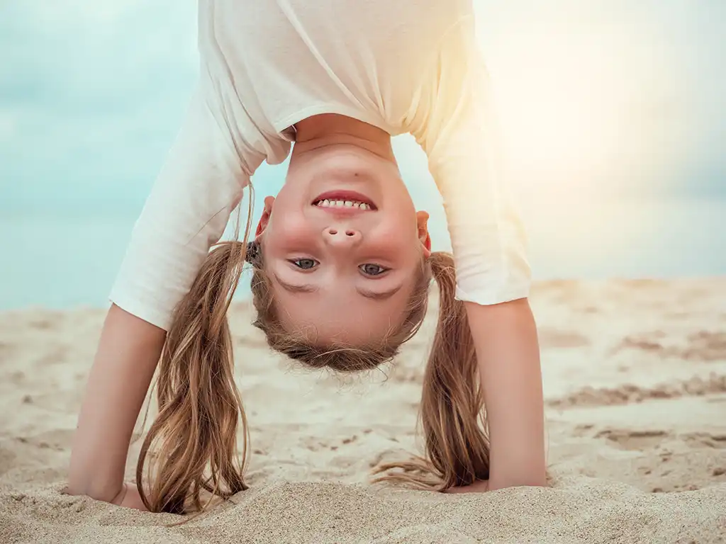 Mädchen im Handstand am Sandstrand